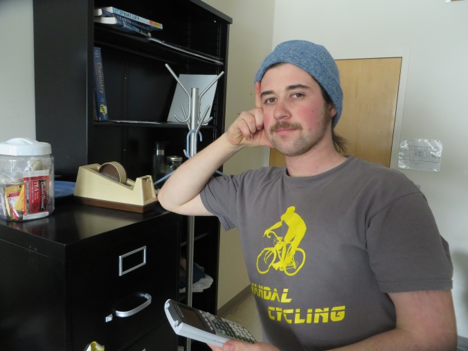 Morra poses for a picture within his office sporting his favorite cycling shirt.